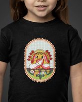 Child wearing a black t-shirt with a colorful graphic design on a dark background